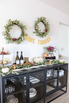 two wreaths hanging on the wall above a buffet table with plates and wine glasses