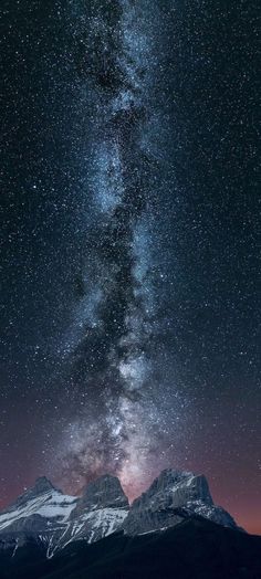 the night sky is filled with stars above mountains and snow - capped peaks in the distance