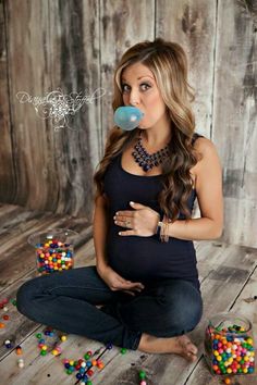 a pregnant woman is sitting on the floor with beads and pacifier in her mouth