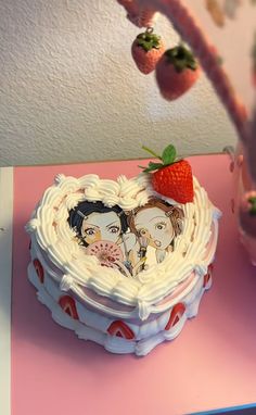 there is a cake with two people on it and strawberries hanging from the tree