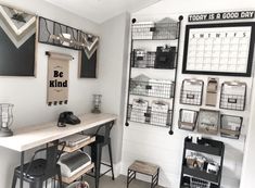 a white room with shelves and baskets on the wall next to a desk, two stools