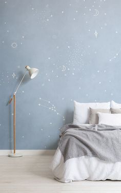 a bedroom with blue walls and stars painted on the wall behind it is a bed