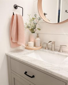 a bathroom with a sink, mirror and towels on the rack next to it's faucet