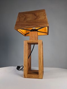 a wooden table lamp sitting on top of a white surface with a cord plugged into it