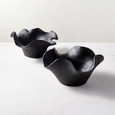 two black bowls sitting on top of a white table