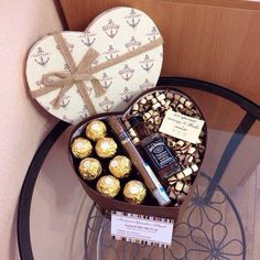 a heart shaped box filled with chocolates and other items on top of a glass table