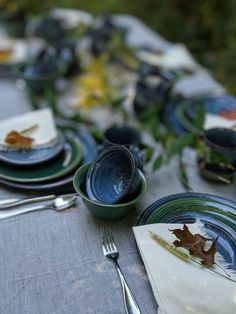 the table is set with plates, silverware and autumn leaves on them for dinner