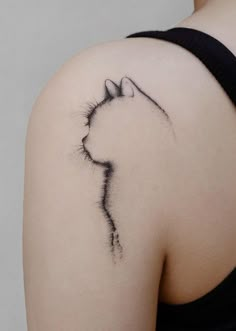 a woman's shoulder with a cat tattoo on it