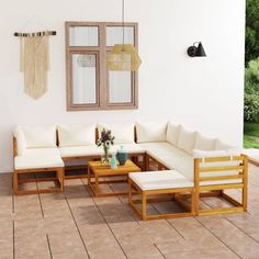 a living room with white couches and wooden tables on the floor next to a window