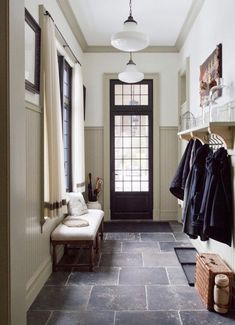 an entry way with clothes hanging on the rack, and a bench next to it