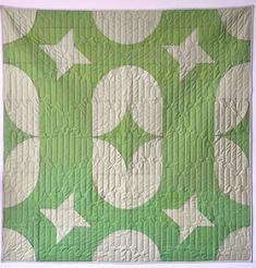 a green and white quilted wall hanging on the side of a building with stars