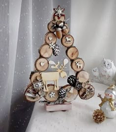 a christmas tree made out of wooden slices and other ornaments on a table next to a snowman figurine