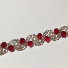 a red and white beaded bracelet with pearls on it's end is shown