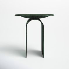 a green table sitting on top of a white floor next to a black object in the middle