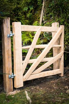 an open wooden gate in front of some trees