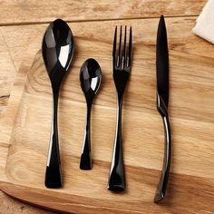 a wooden cutting board topped with black utensils