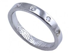 a white gold ring with three diamonds on the inside and in the outside, made to look like fingerprints