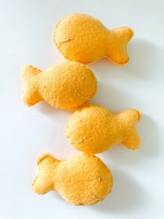 three yellow fish shaped pastries on a white surface