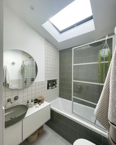 a bathroom with a skylight above the sink and bathtub, toilet and shower