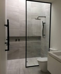 a bathroom with a toilet, sink and shower in it's glass door area