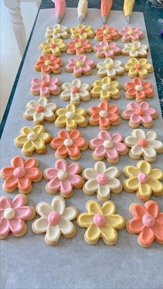 decorated cookies on a table with pink, yellow and white icing in the shape of flowers