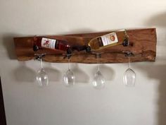 three wine glasses hanging from a wooden rack on the wall next to four wine glasses