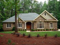 a large brick house with lots of windows and trees in the front yard, surrounded by mulch