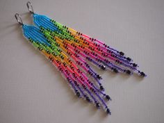 multicolored beaded earrings hanging from hooks on a white tablecloth with black beads