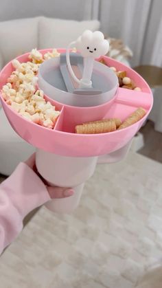 a pink cup filled with food and a small figure on top of the cup holder