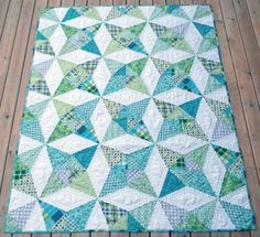 a green and white quilt sitting on top of a wooden floor