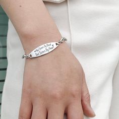 a woman wearing a bracelet with an engraved message