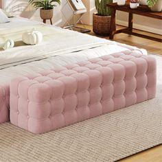 a large pink bed sitting on top of a wooden floor next to a white rug