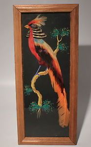 a painting of a bird sitting on a tree branch in a wooden frame with a white wall behind it