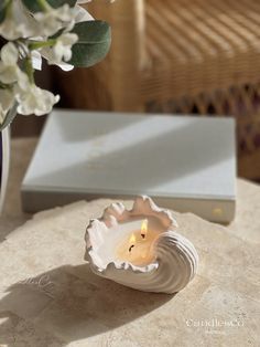 a white candle sitting on top of a table next to a vase filled with flowers