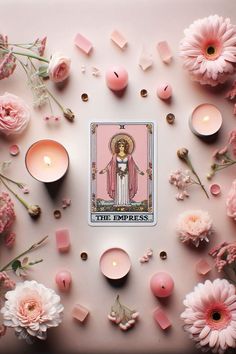 a tarot card surrounded by pink flowers and candles