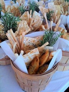 baskets filled with different types of food on top of a white tablecloth covered table