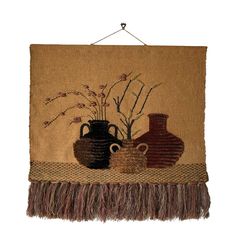 a wall hanging with two vases and flowers on it's fringed edge