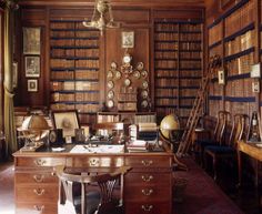 an old library with lots of books on the shelves and desk in front of it