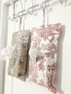 two bags hanging from hooks on a white door with red and white wallpaper in the background