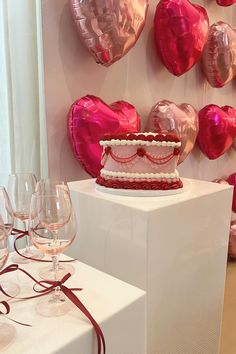 a red and white cake sitting on top of a table next to some wine glasses