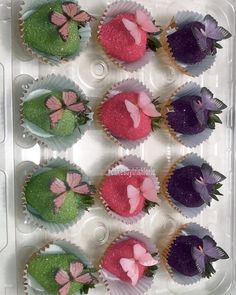 cupcakes decorated with pink, purple and green icing in a plastic container