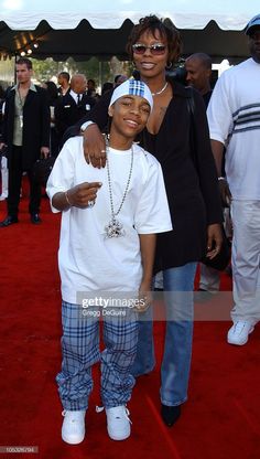 two people standing on a red carpet with one person wearing sunglasses and the other holding his arm around another person's shoulder