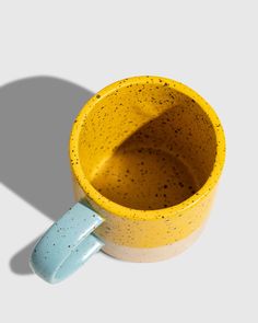 a yellow and blue coffee cup with a spoon in it