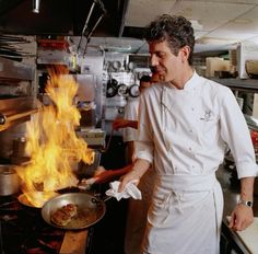 a man cooking food in a kitchen with flames coming out of the stove and on fire