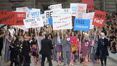 a group of people walking down a street holding signs