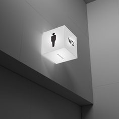 a white light hanging from the side of a wall next to a toilet paper dispenser