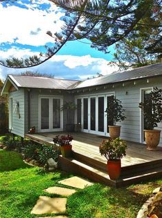 a house with a deck and potted plants on the lawn