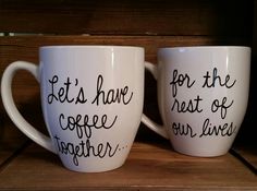 two coffee mugs with writing on them sitting on a wooden shelf next to each other