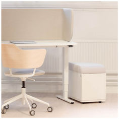 an office chair and desk with a laptop on it, in front of a white wall