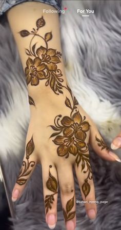 a woman's hand with henna tattoos on her arm and hands, all decorated with flowers